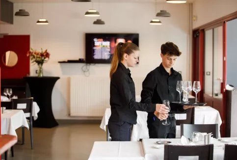 Deux jeunes en train de préparer une table de restaurant 