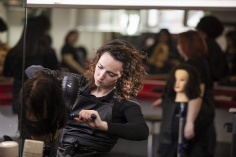 Une élève qui coiffe une cliente